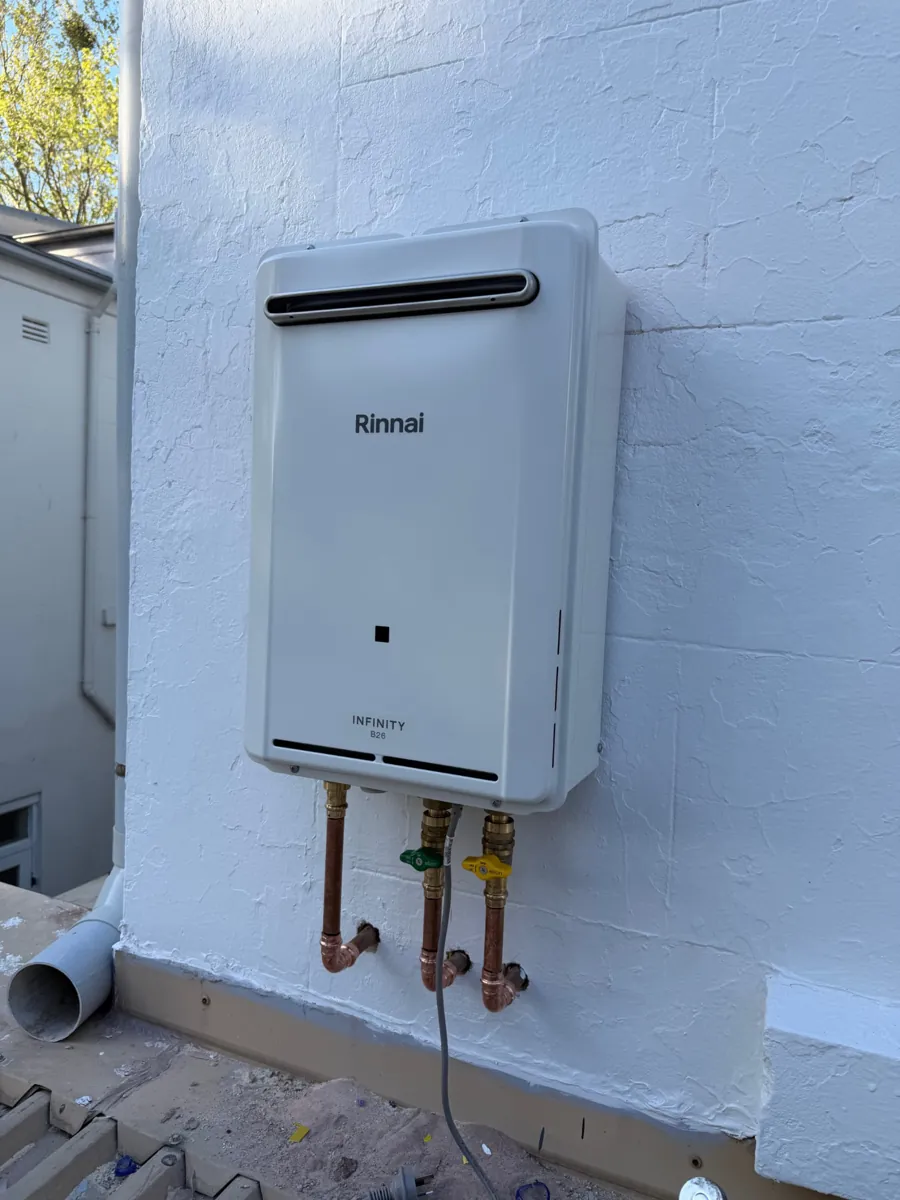 Rinnai Infinity B26 hot water system installed on a white wall with copper pipework